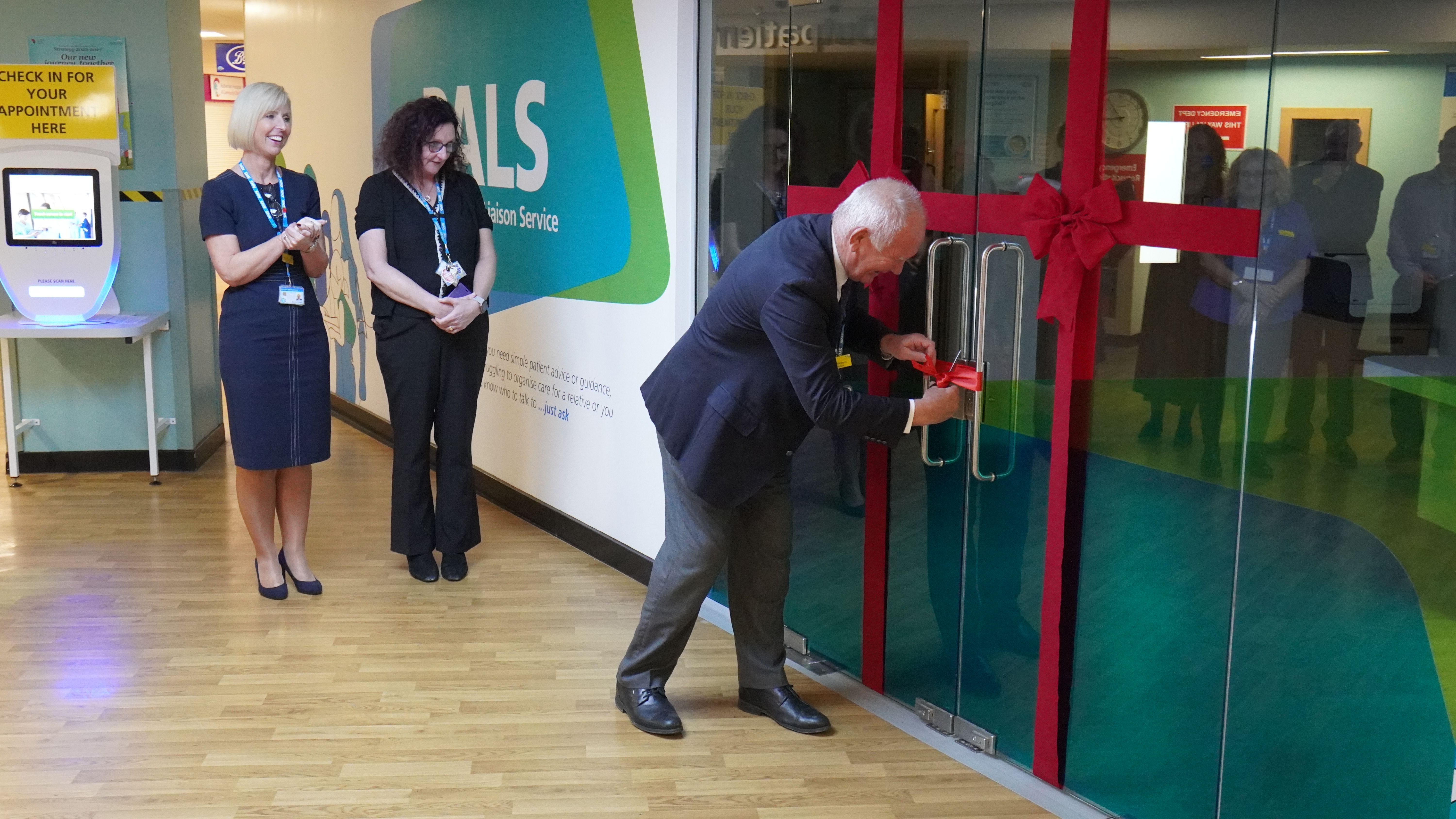 Dr Mike Richmond is cutting a red ribbon on the door of the PALS office