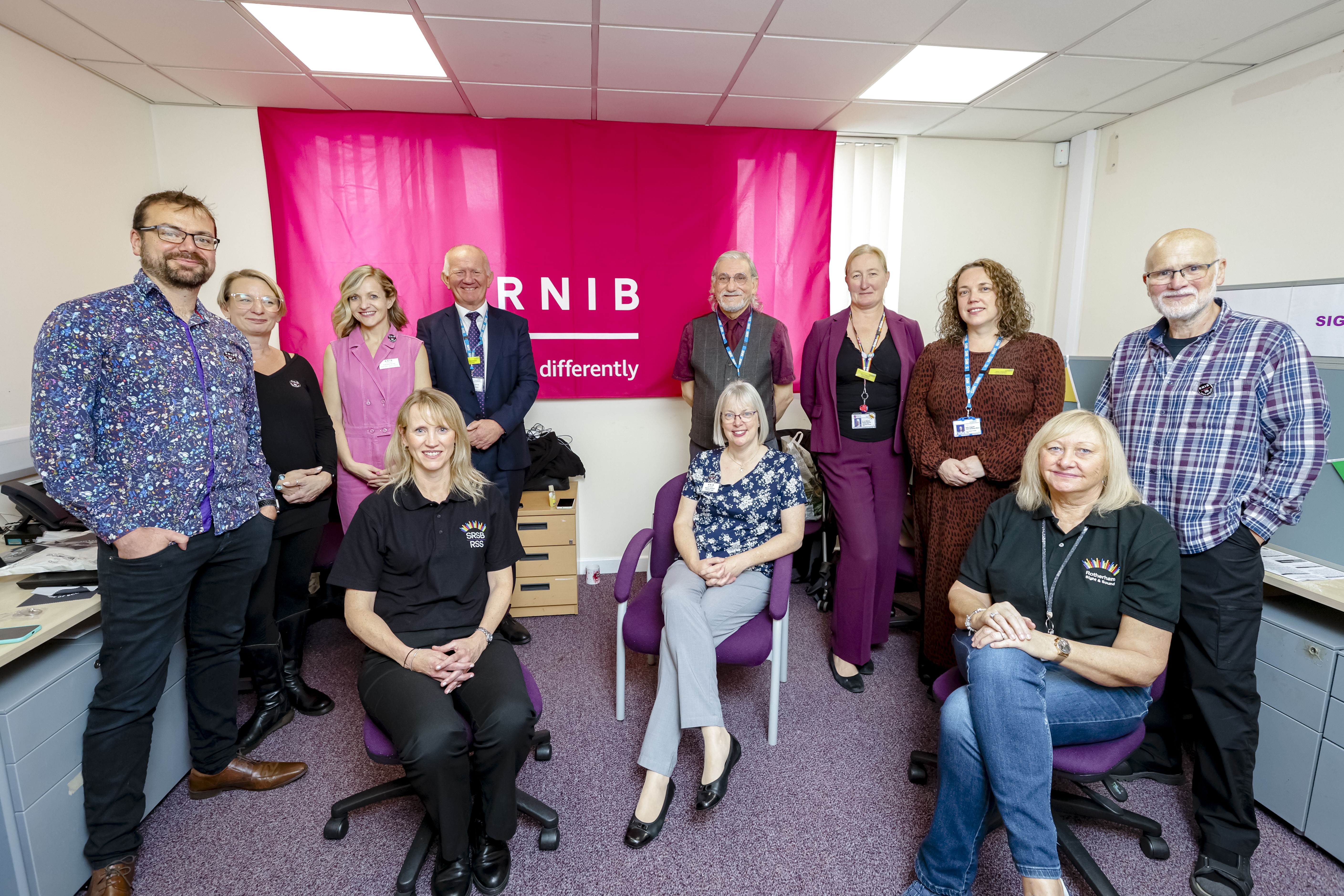 A group of people in front of a pink RNIB banner 