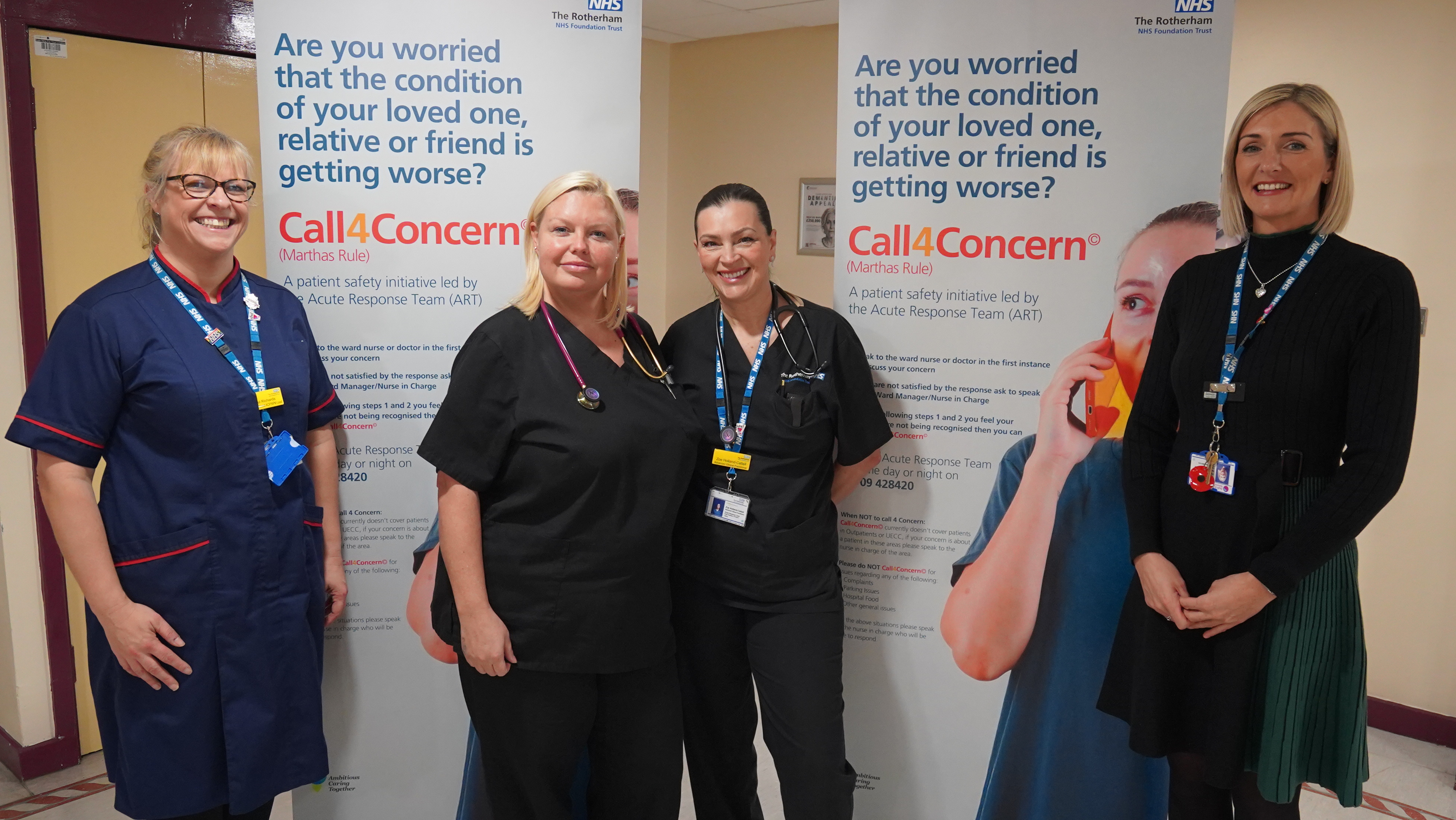 Four female clinical colleagues are stood in front of two pull-up banners promoting Call 4 Concern 