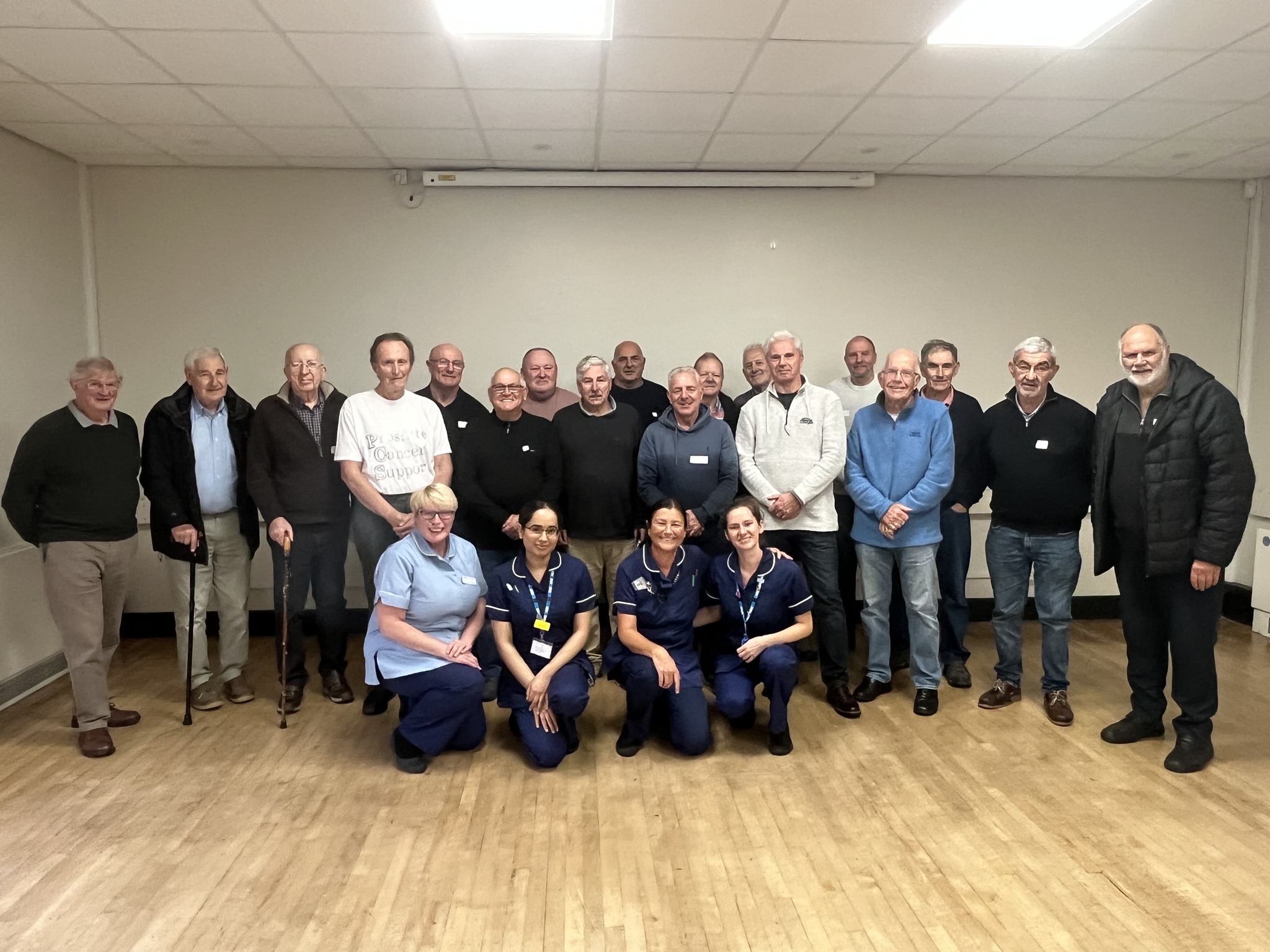 A group of men and four healthcare workers smile at the camera