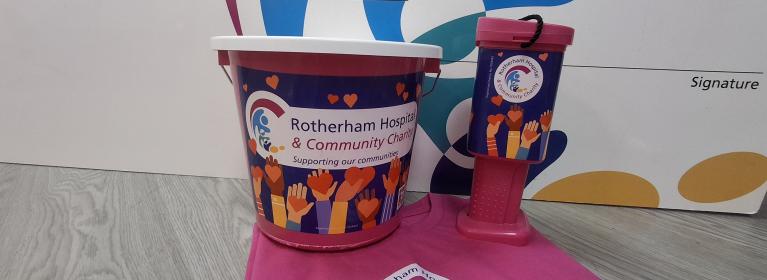 Pink charity branded collection buckets stood on a folded pink charity branded tshirt