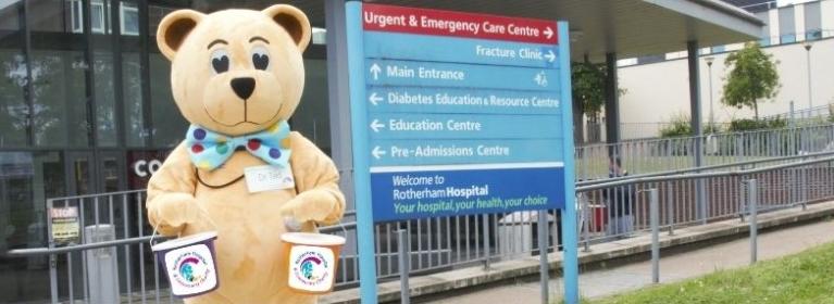 Dr Ted outside Rotherham Hospital's main entrance holding two charity donation buckets