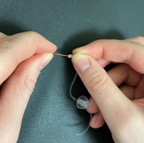 Inserting a cleaning rod into the hearing aid tubing