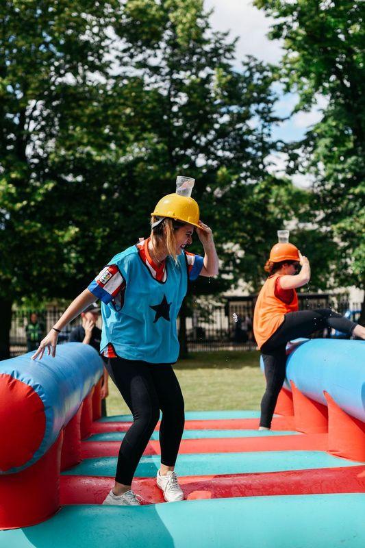 Two people wearing hard hats on an inflatable obstacle